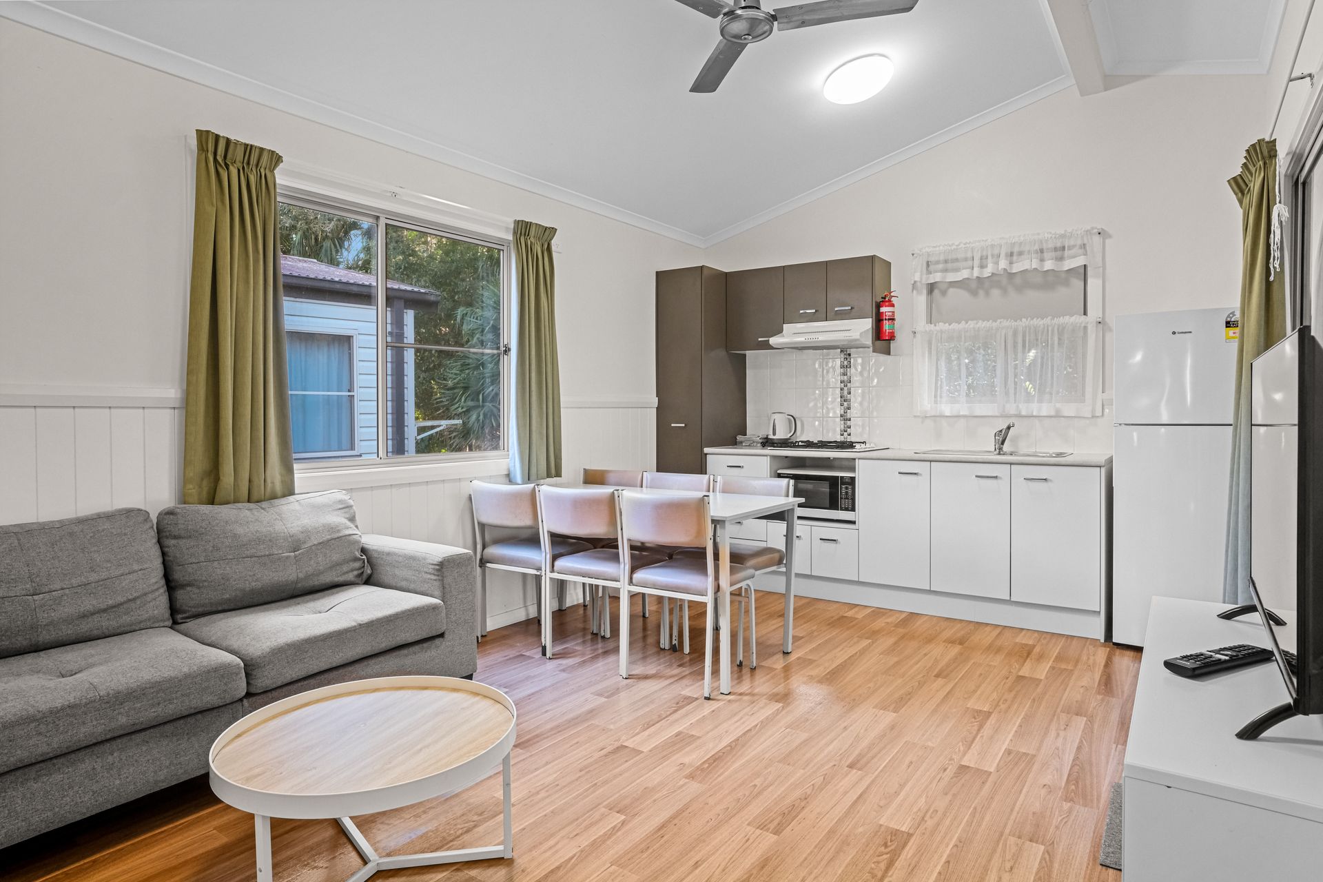 A Hotel Room With A Chair , Table And Window — Pacific Palms Caravan Park in Elizabeth Beach, NSW