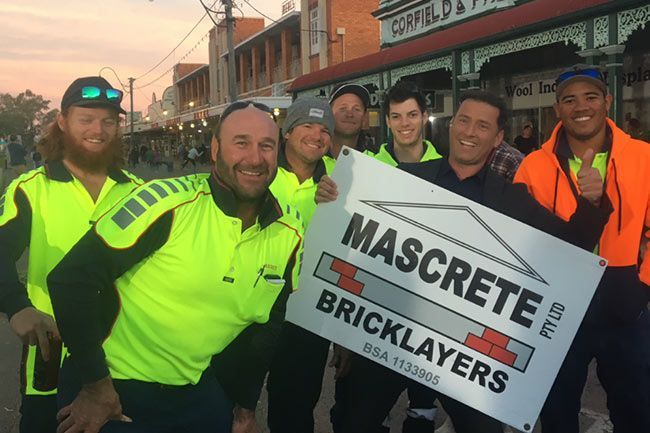 A Group Of Men Are Holding A Sign That Says Mascrete Bricklayers — Mascrete Pty Ltd In Hermit Park, QLD
