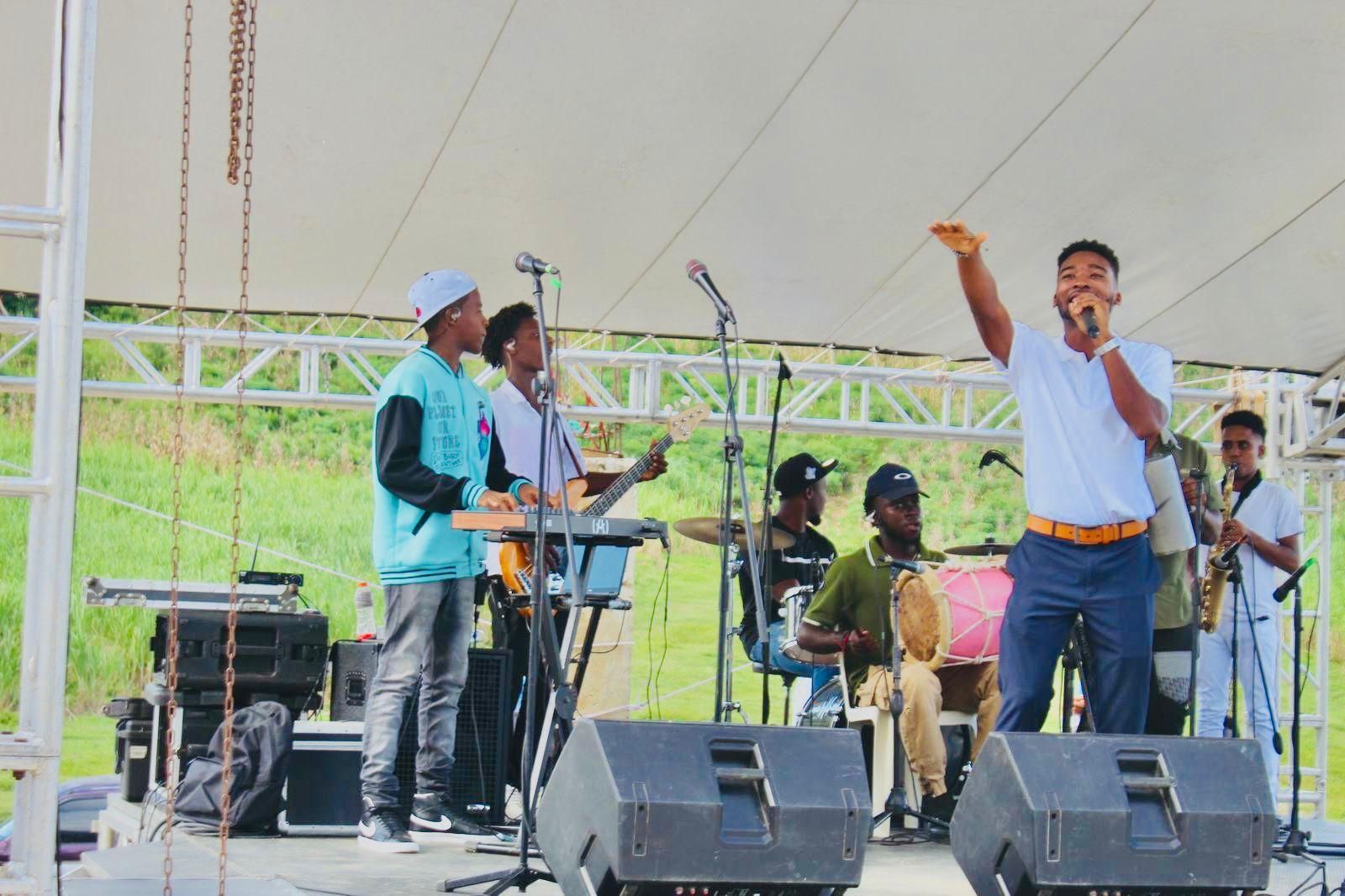 A man is singing into a microphone on a stage with a band behind him.