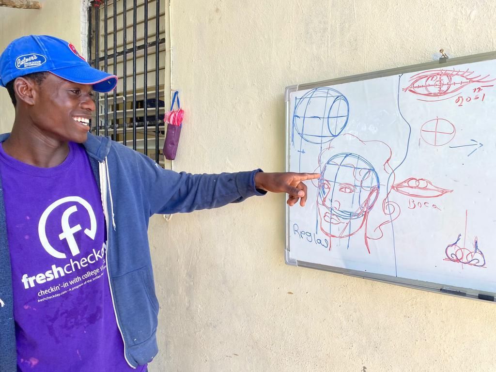 A man in a purple shirt is pointing at a whiteboard.