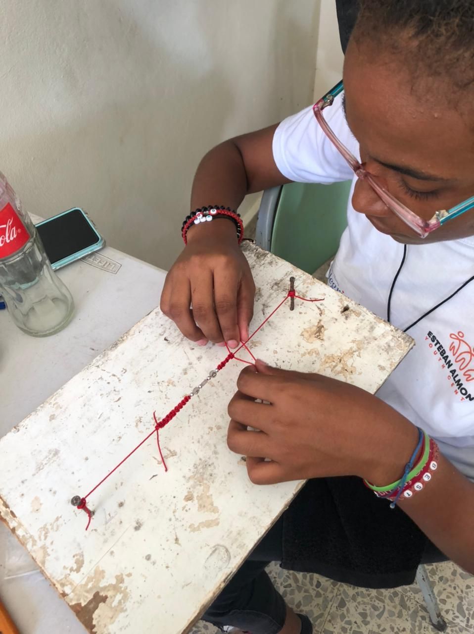 A young girl is working on a project with a coca cola bottle in the background