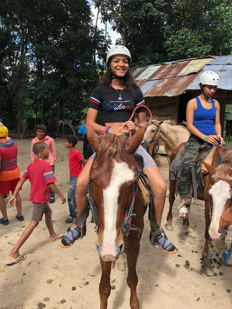 A young girl is riding a horse in a dirt field.