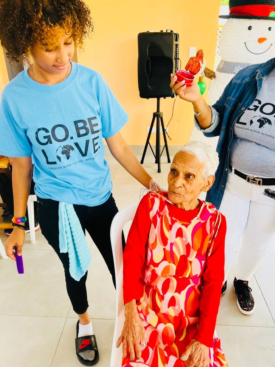 A woman wearing a blue shirt that says go be love