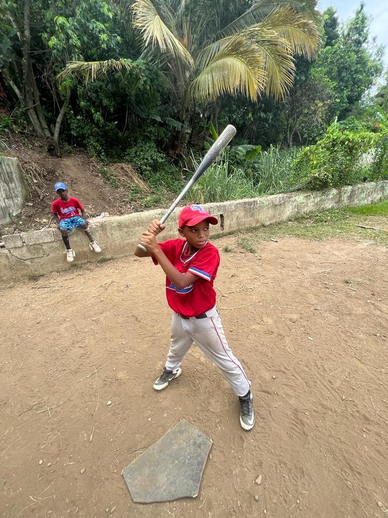 A young boy is swinging a baseball bat on a dirt field.