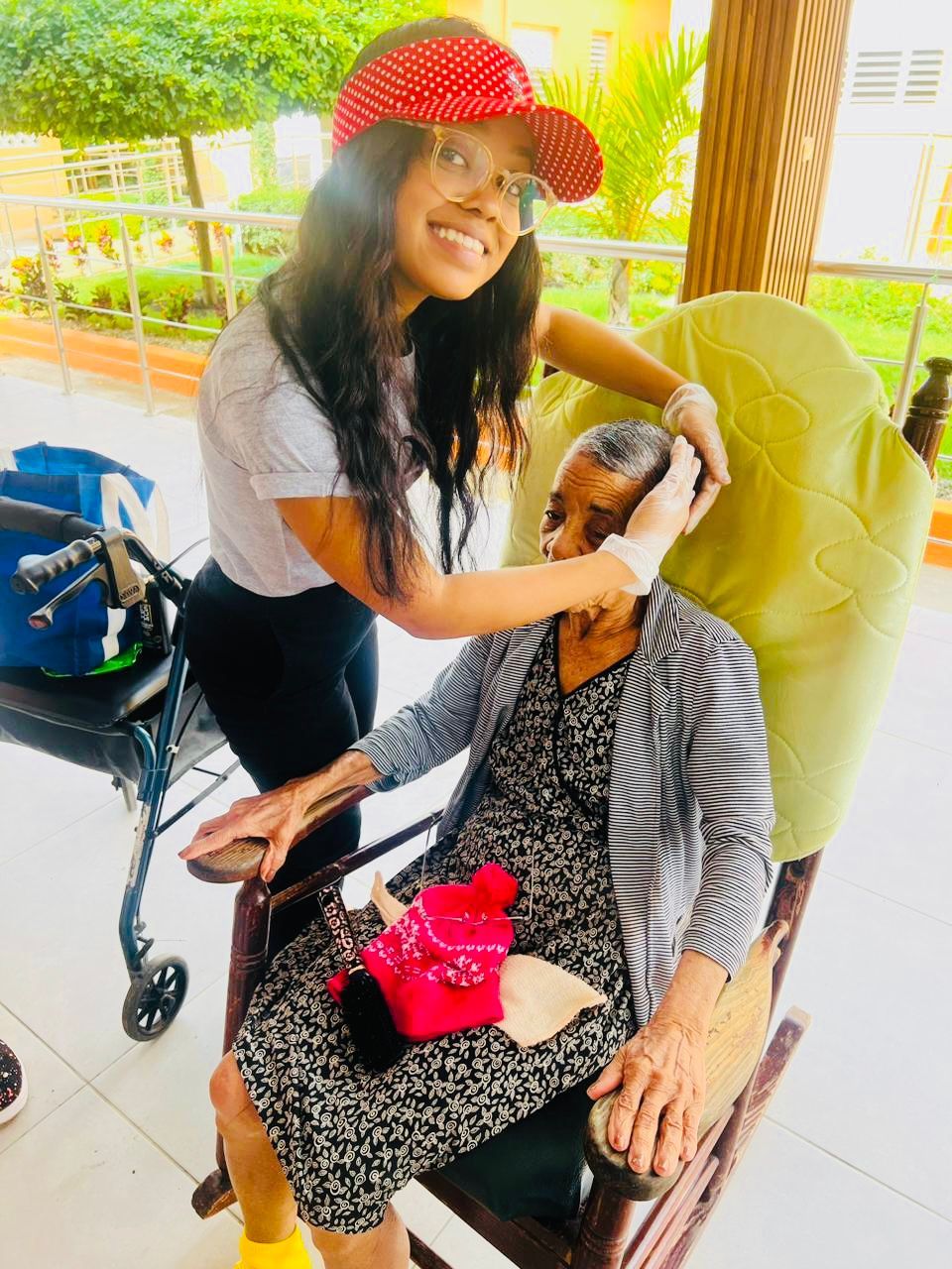 A woman is helping an elderly woman in a rocking chair.