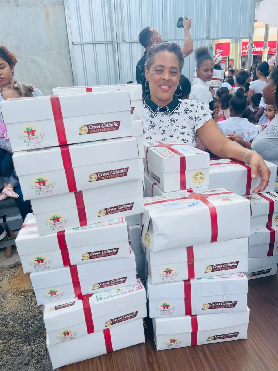 A woman is standing in front of a stack of boxes.