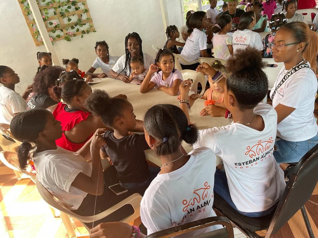 A group of children are sitting around a table in a circle.