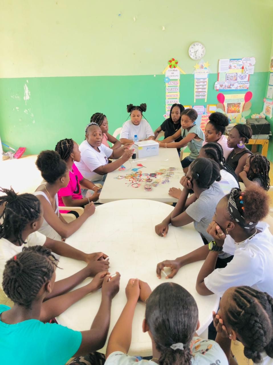 A group of children are sitting around a table holding hands