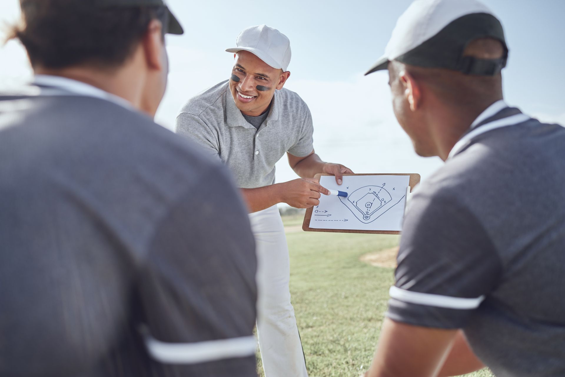 Coach showing play diagram to team members on a field.