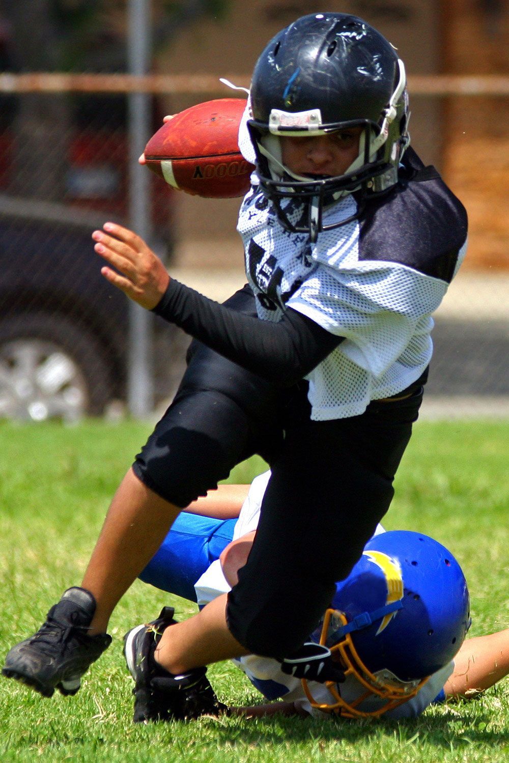Football player running with ball, being tackled on a green field.