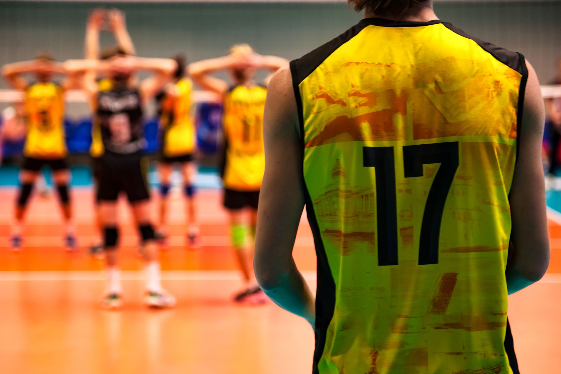 Volleyball player wearing a yellow jersey with the number 17, facing teammates on the court.