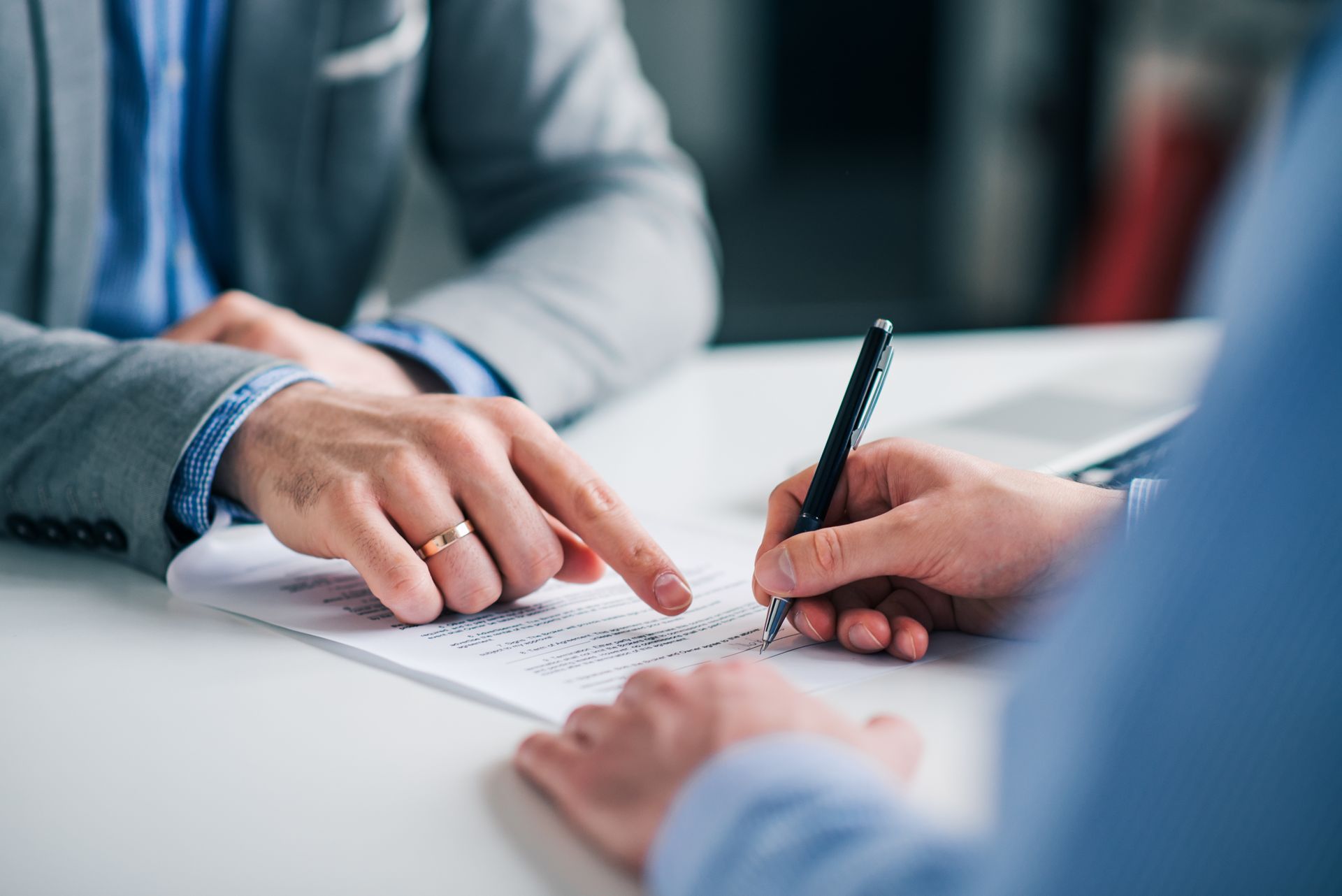 Two people in suits signing a document at a table during a business meeting