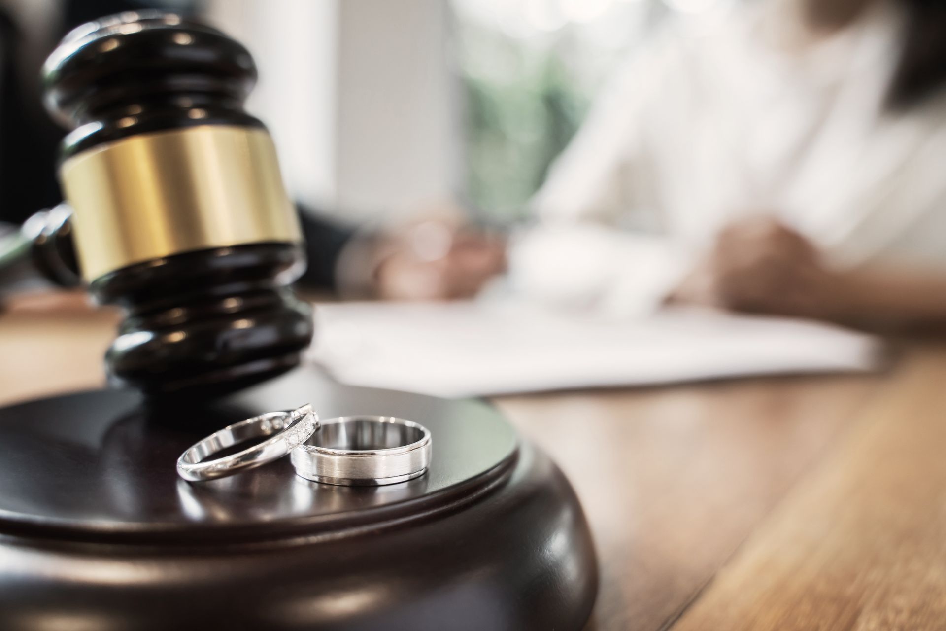 Judge’s gavel beside wedding rings on a desk in a courtroom setting