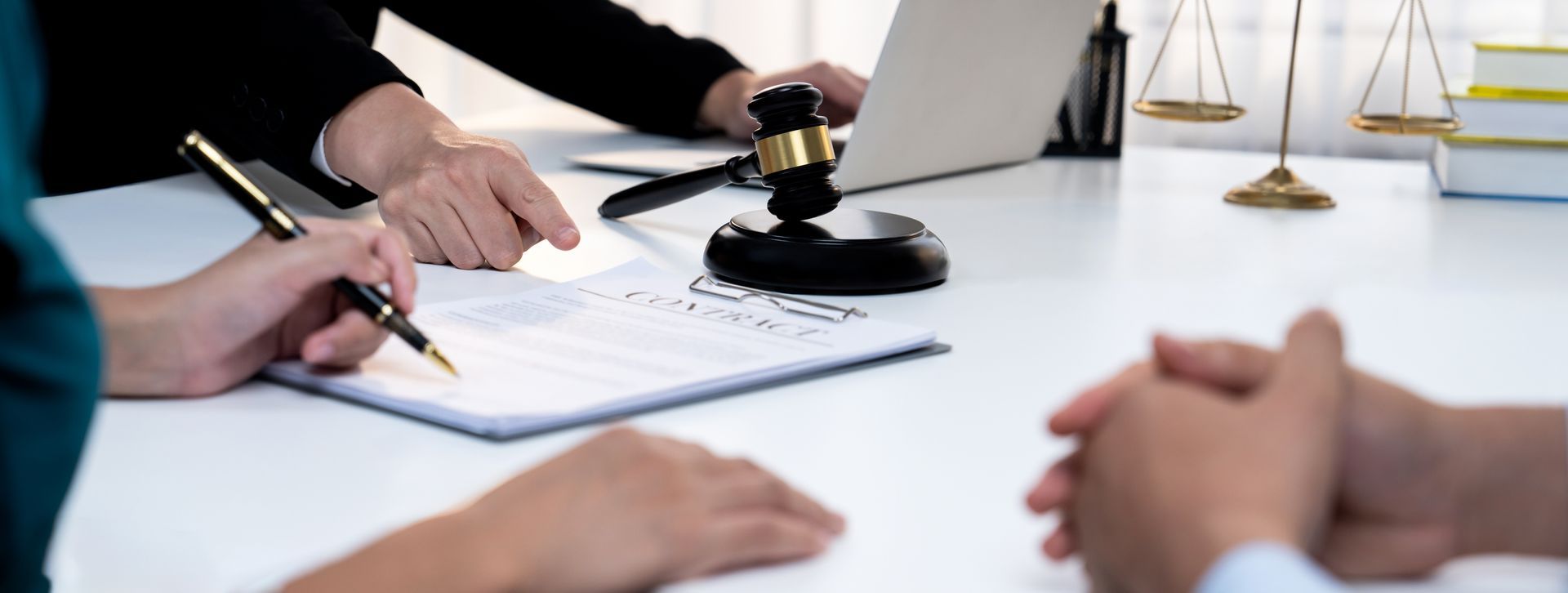 Business meeting with people taking notes around a laptop and legal scales on a conference table