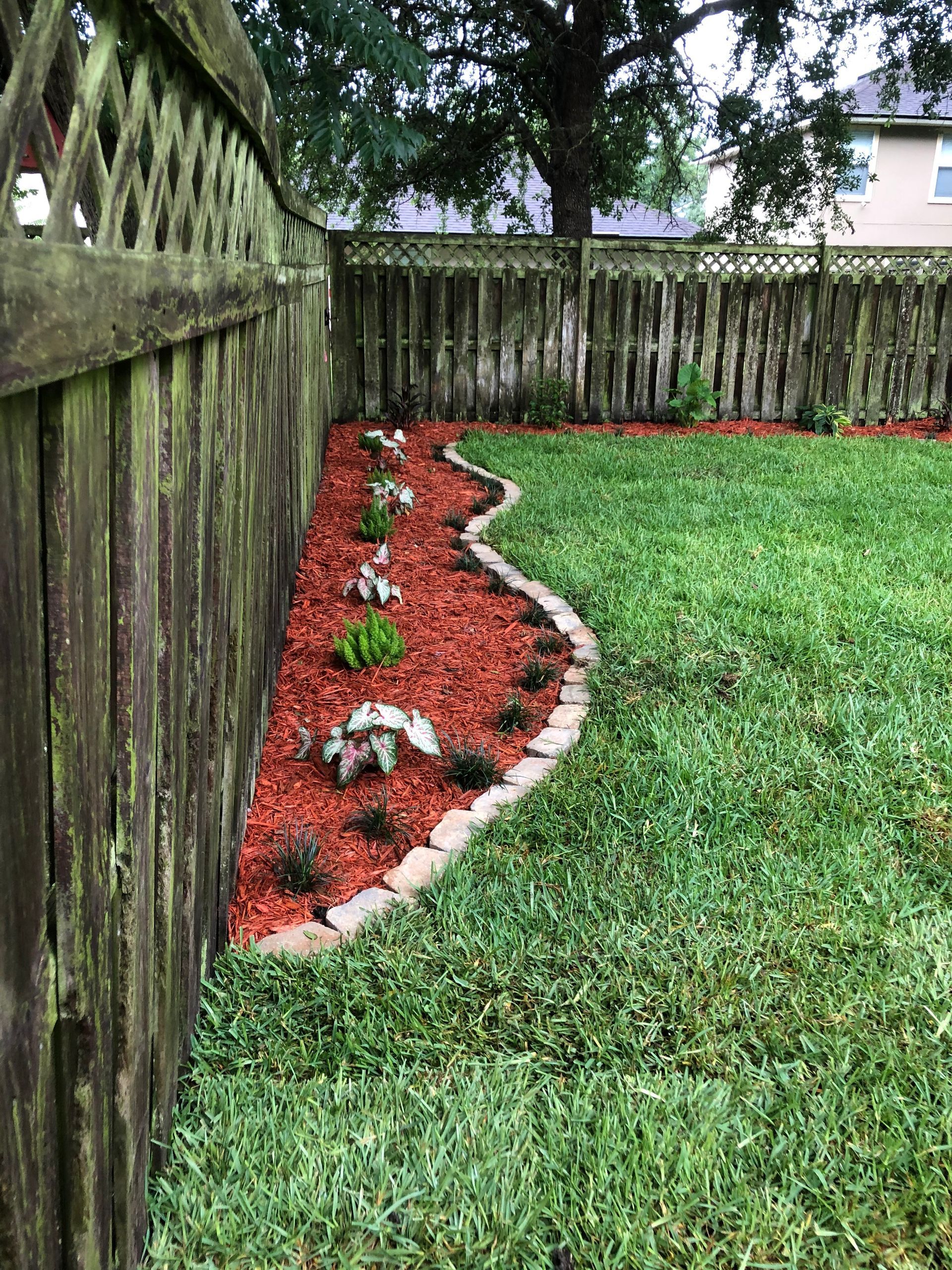 A wooden fence is surrounded by a lush green lawn.