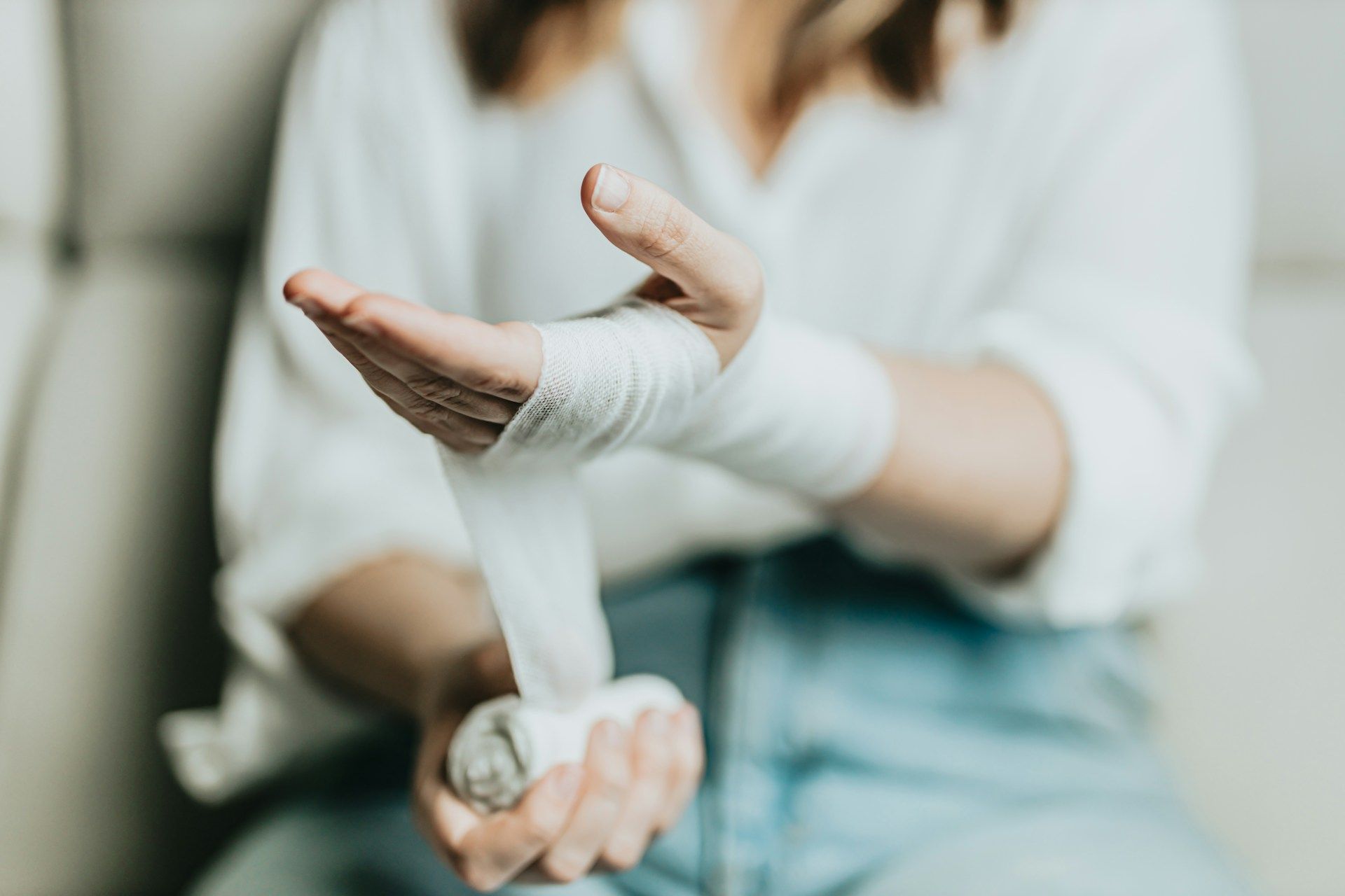 Person wrapping a white bandage around a wrist.