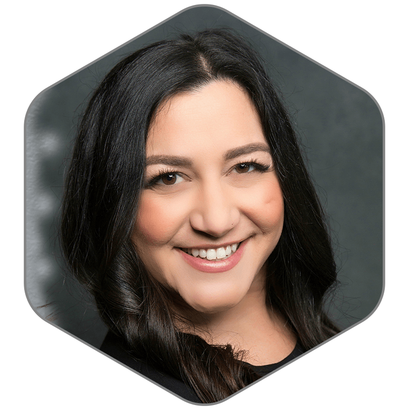 A woman with long dark hair is smiling in a hexagon shape