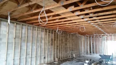 Unfinished room with exposed wooden ceiling joists, framed walls, and construction debris.