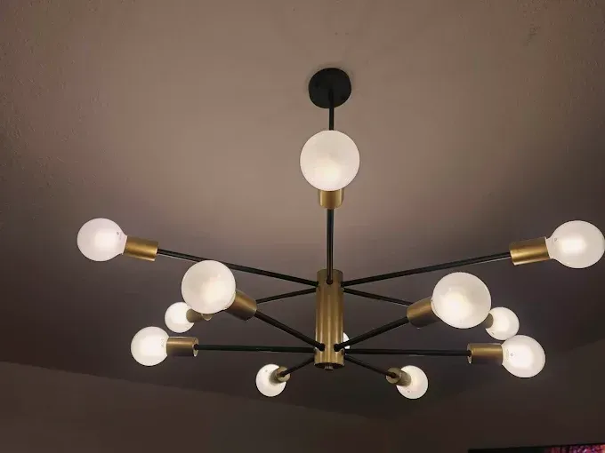 Modern brass chandelier with multiple white globe bulbs on a ceiling