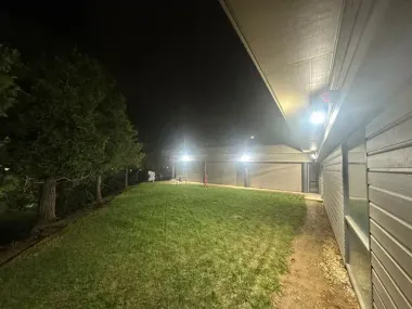 Foggy nighttime view of a grassy slope beside a building, lit by bright outdoor lights