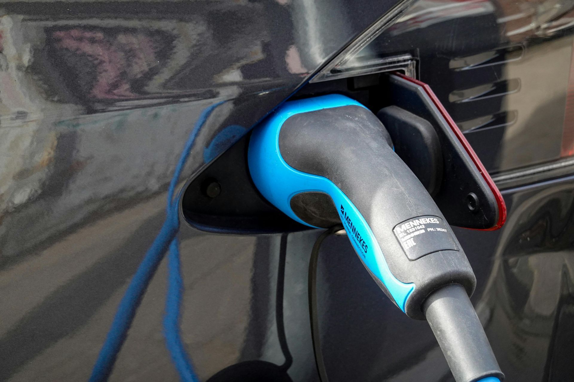 Electric vehicle charging plug inserted into a black car’s charging port