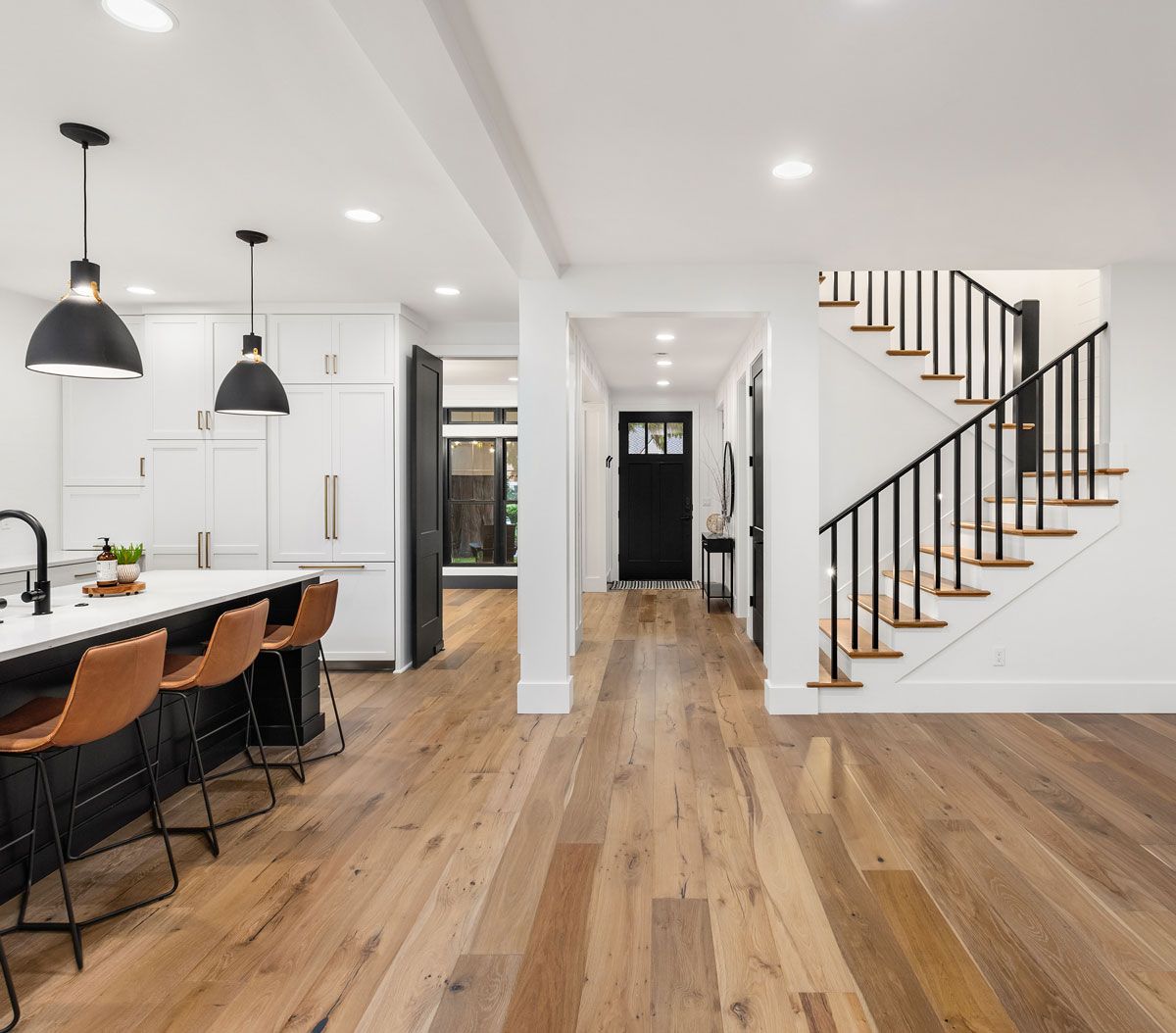 A kitchen with hardwood floors and a staircase leading up to the second floor.