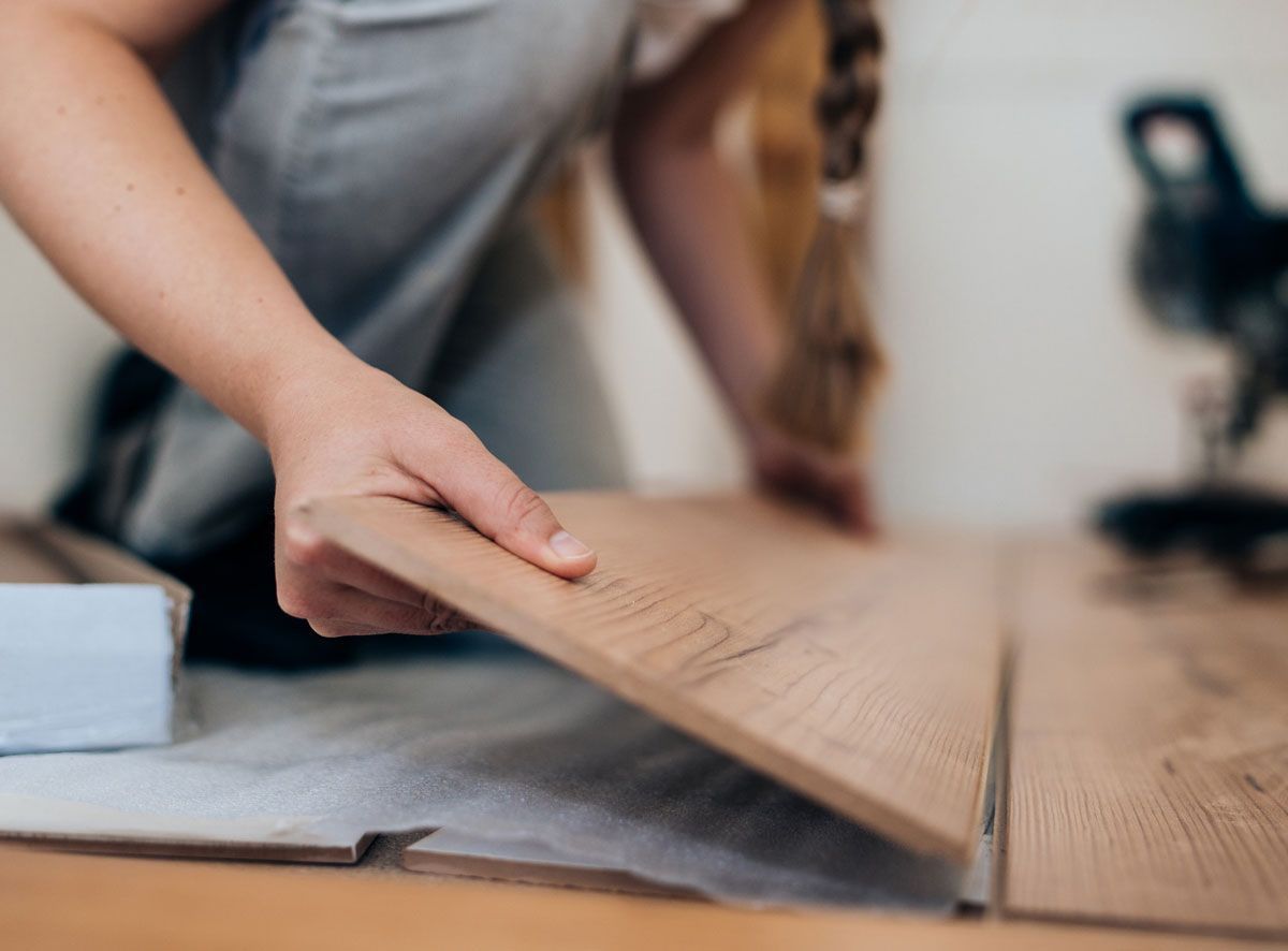 A person is laying a piece of wood on a table.