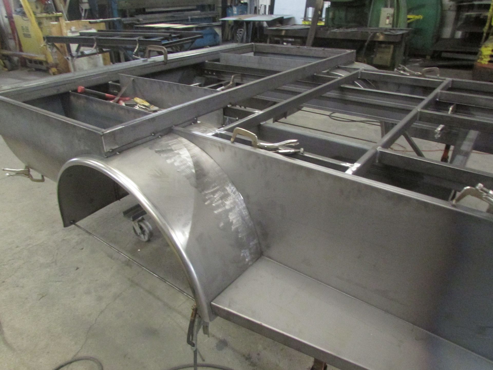 A man is welding a piece of metal on a table in a factory.