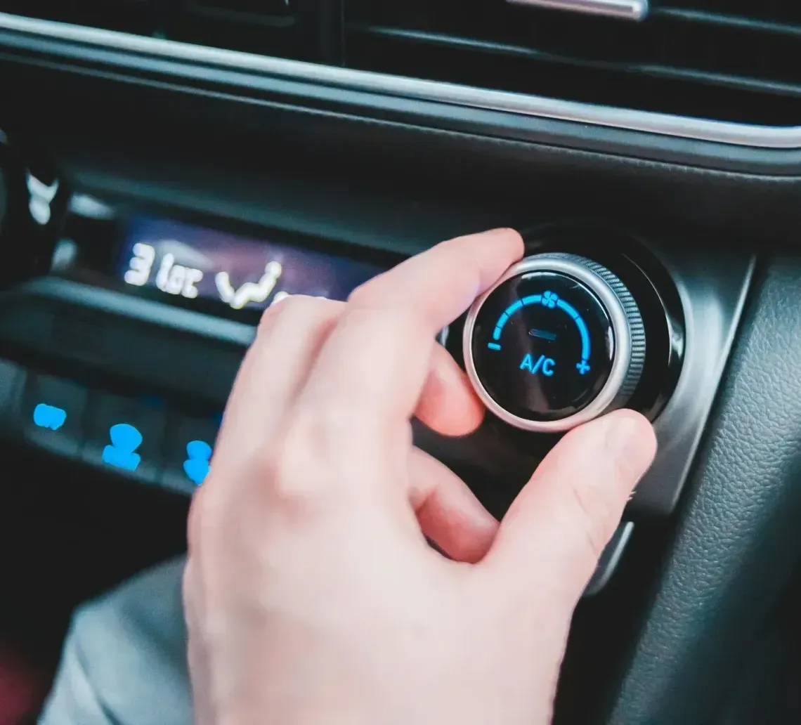 Hand turning car air conditioning dial.