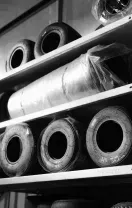 Shelves filled with various tires, some wrapped in plastic, in a storage room.