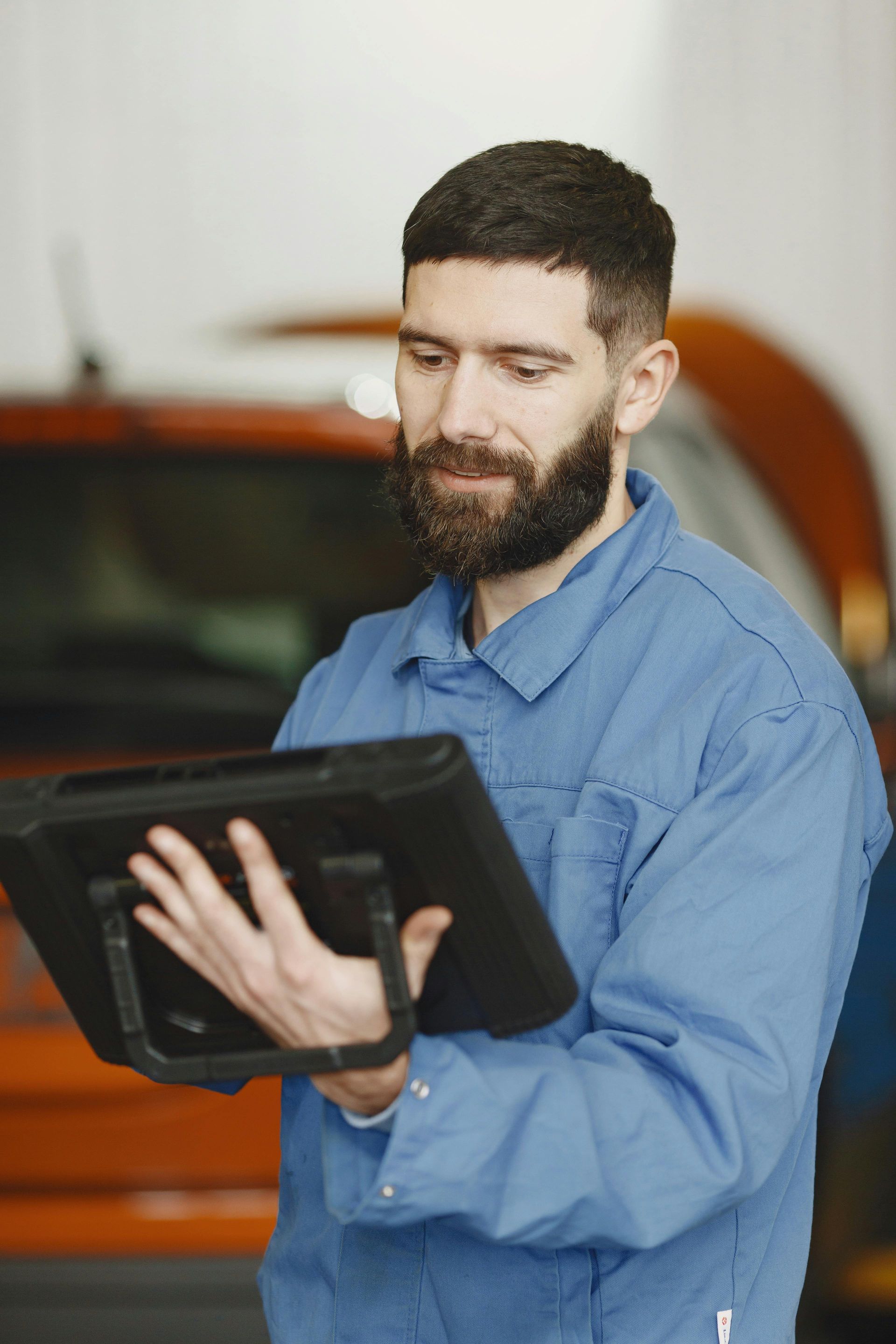 Mechanic inspecting car brake rotor on a vehicle lift.