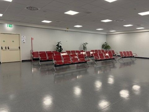 Una sala d'attesa vuota con sedie rosse e una porta.