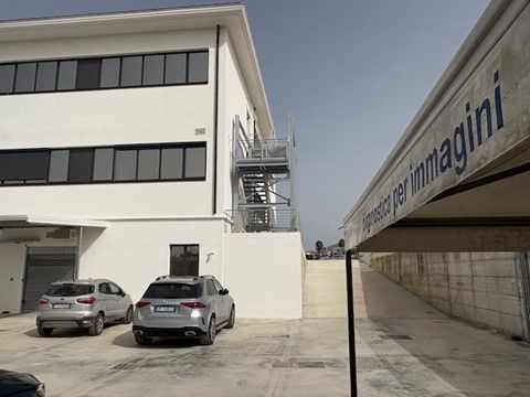 Un edificio bianco con le auto parcheggiate davanti.
