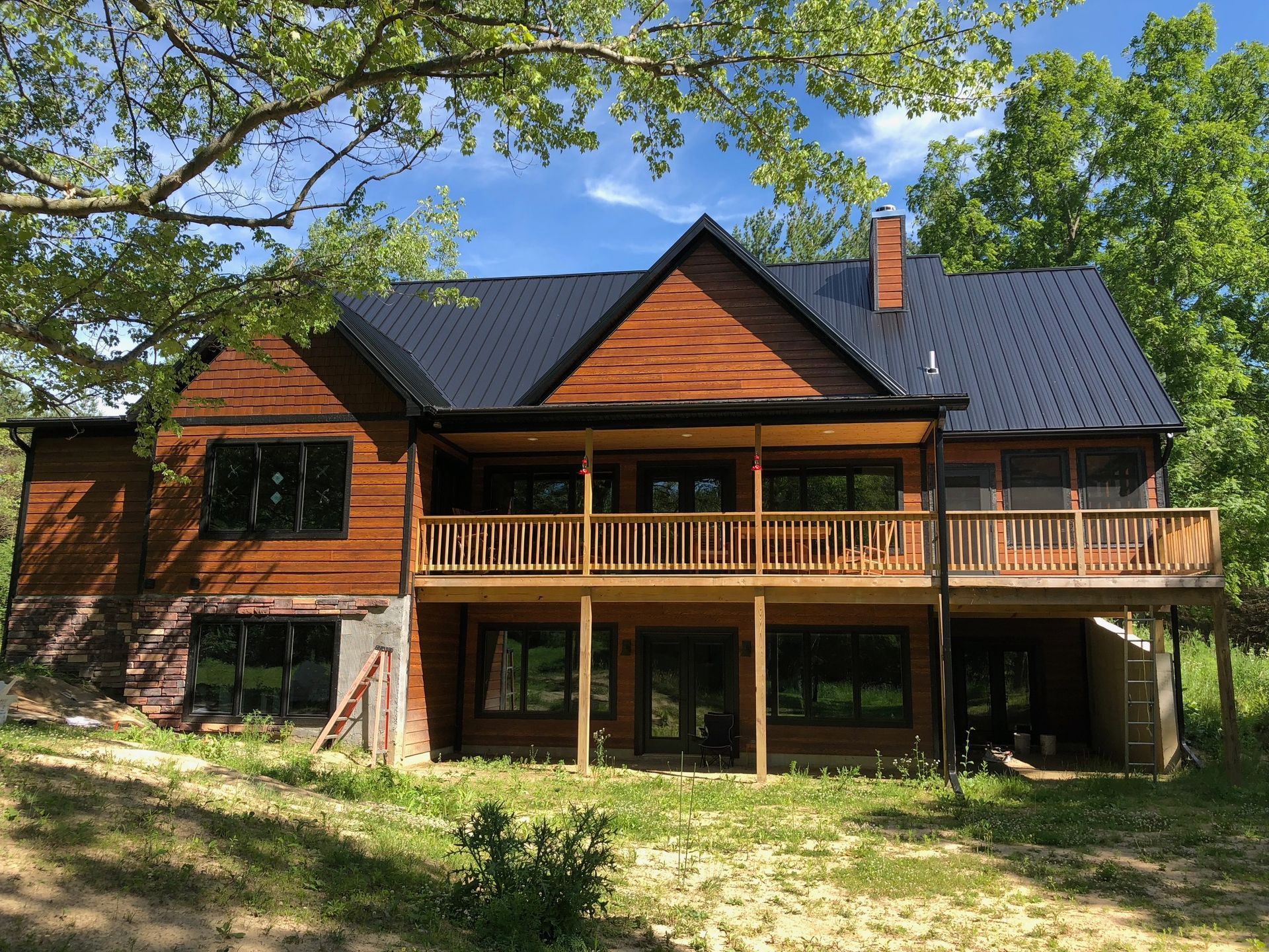 A large wooden house with a black roof and a large deck