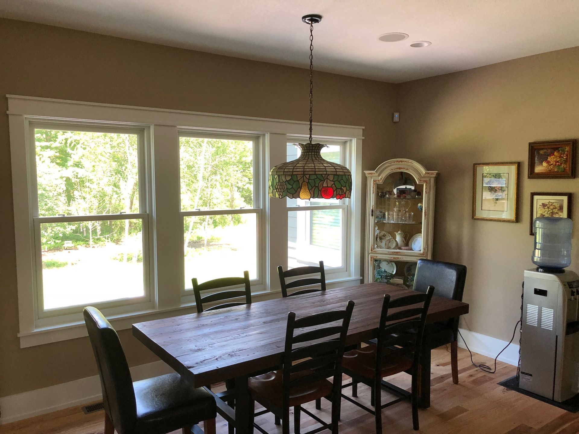 A dining room with a wooden table and chairs and a chandelier hanging from the ceiling.
