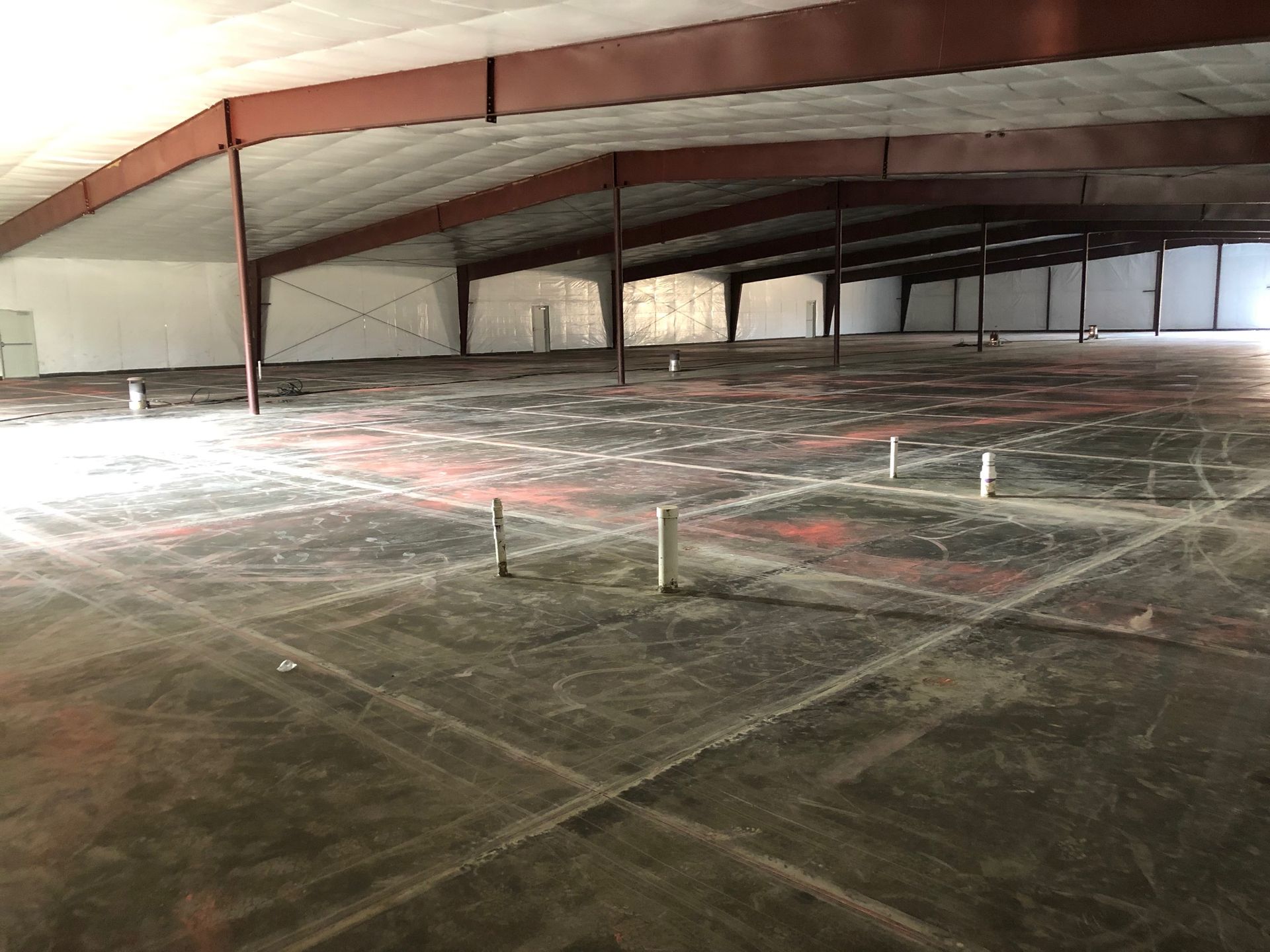 A large warehouse with a concrete floor and a metal roof.