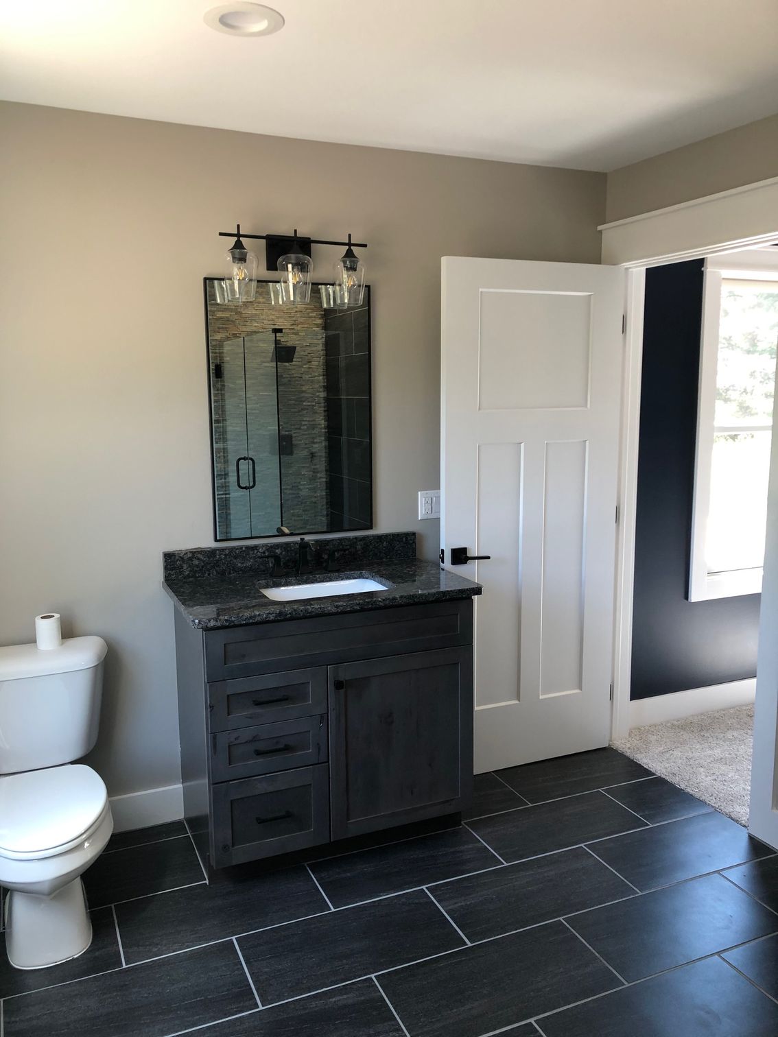 A bathroom with a toilet , sink and mirror.