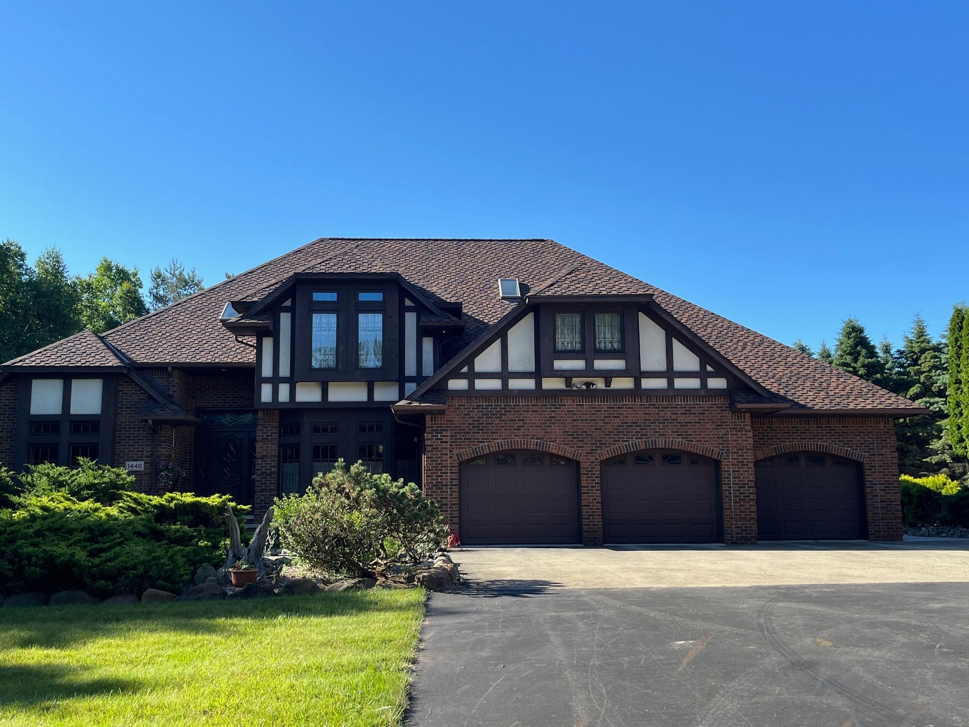 A large brick house with three garage doors and a driveway
