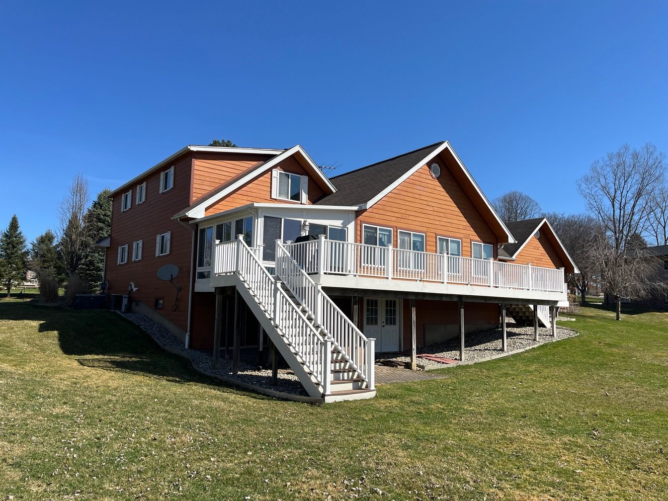 The back of a large house with a large deck and stairs.
