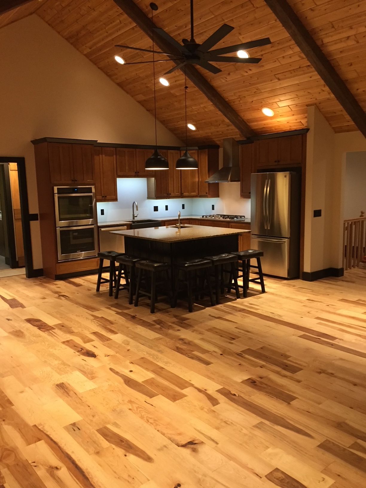A kitchen with wooden floors and a ceiling fan