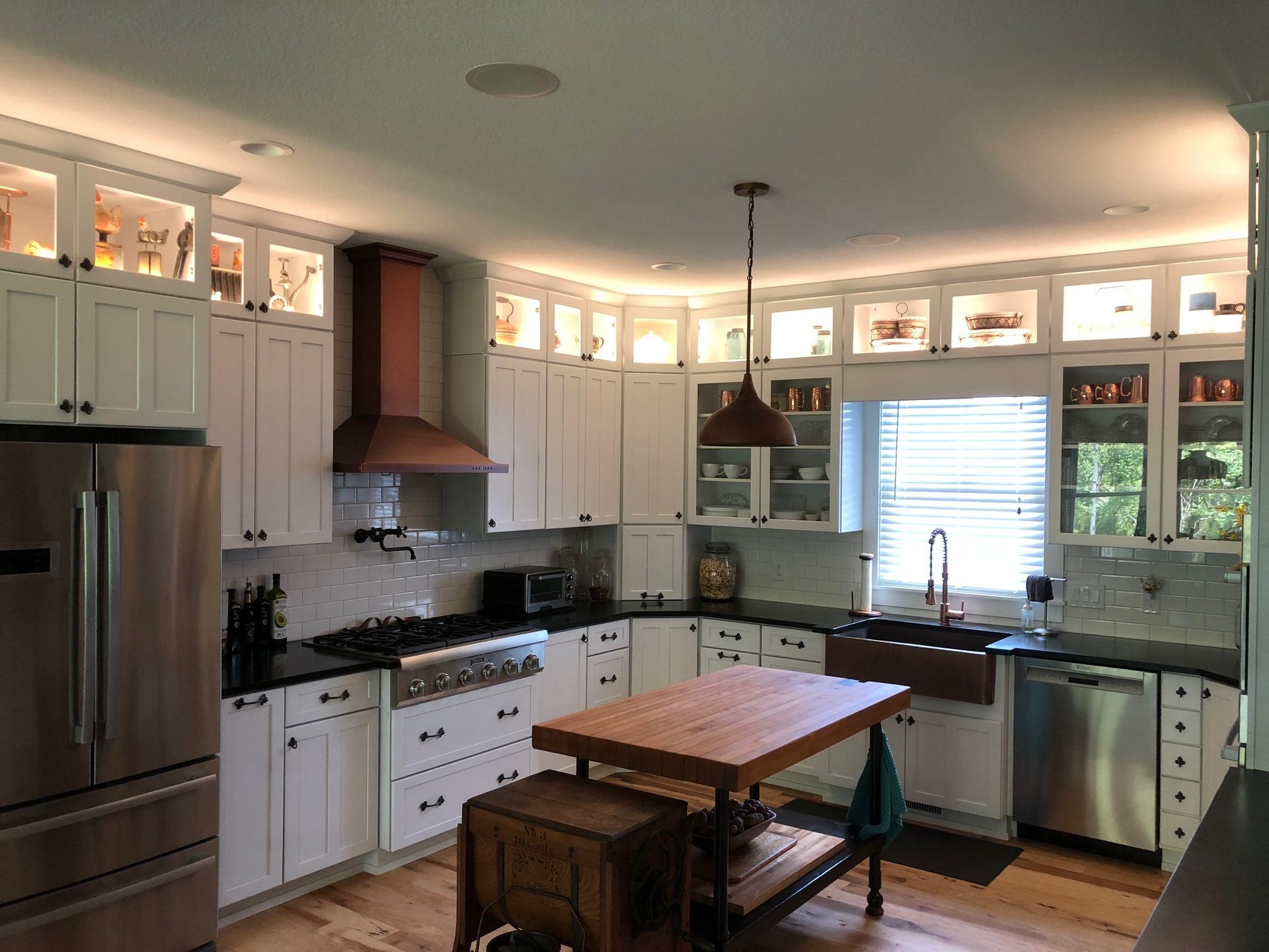 A kitchen with white cabinets , stainless steel appliances , and a wooden table.