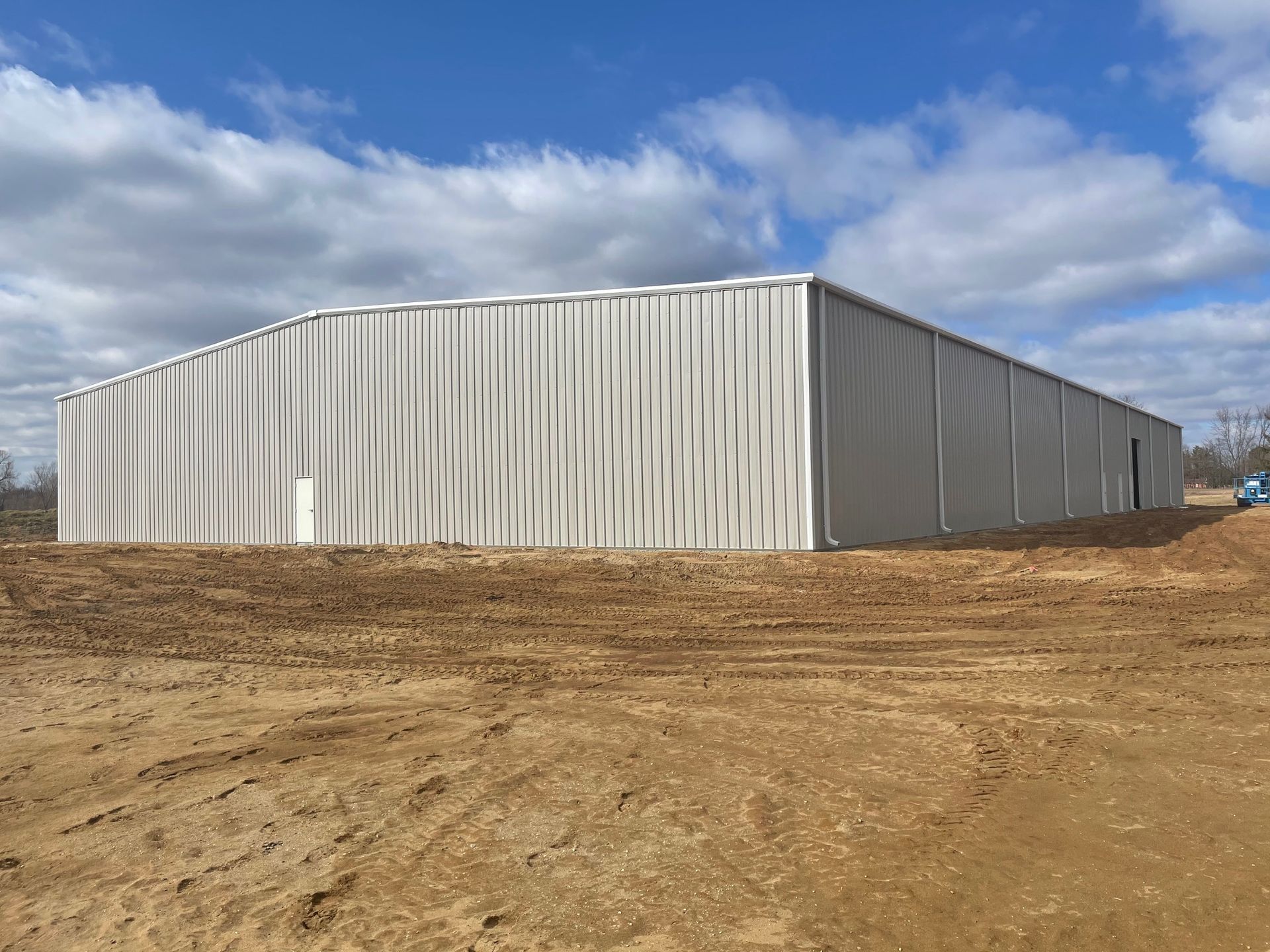 A large white building is sitting in the middle of a dirt field.