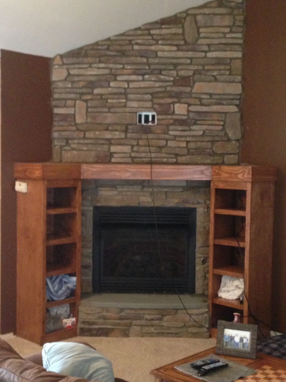 A living room with a stone fireplace and shelves