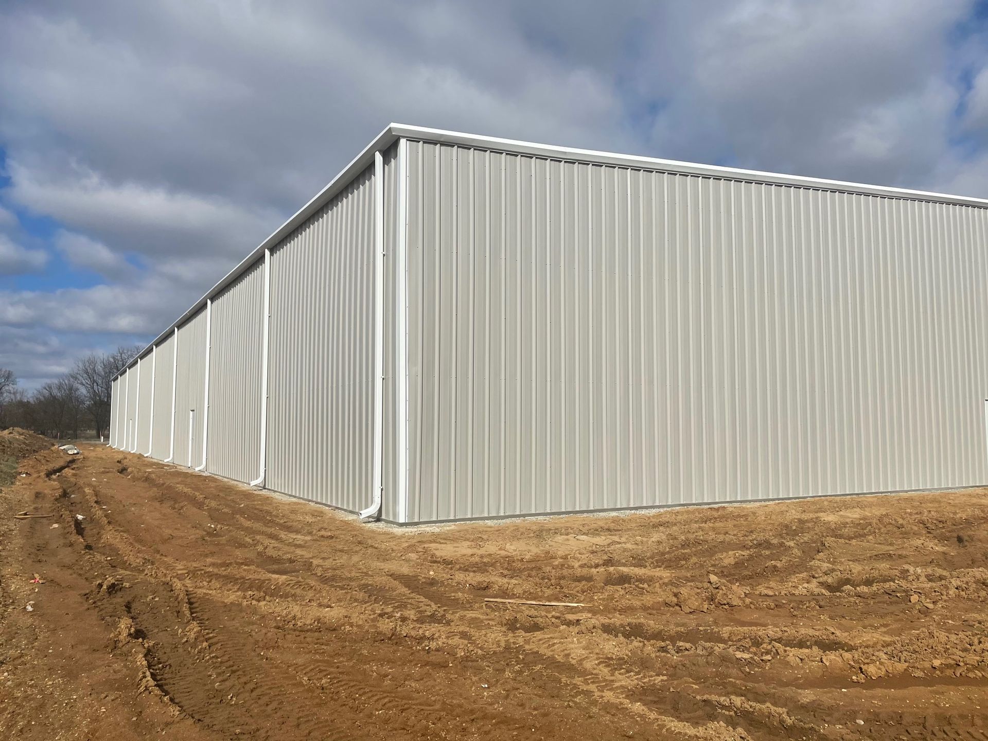 A large white building is sitting on top of a dirt field.