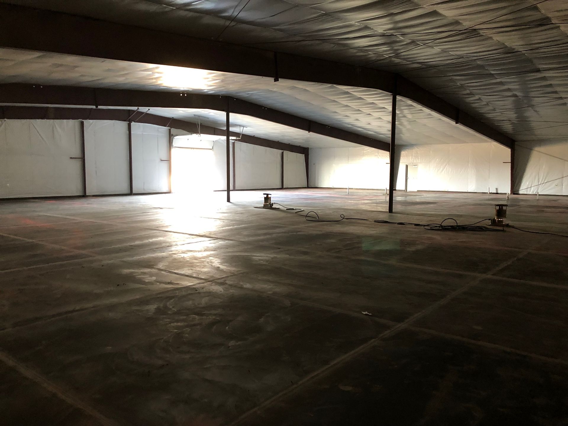 A large empty warehouse with a concrete floor and white walls.