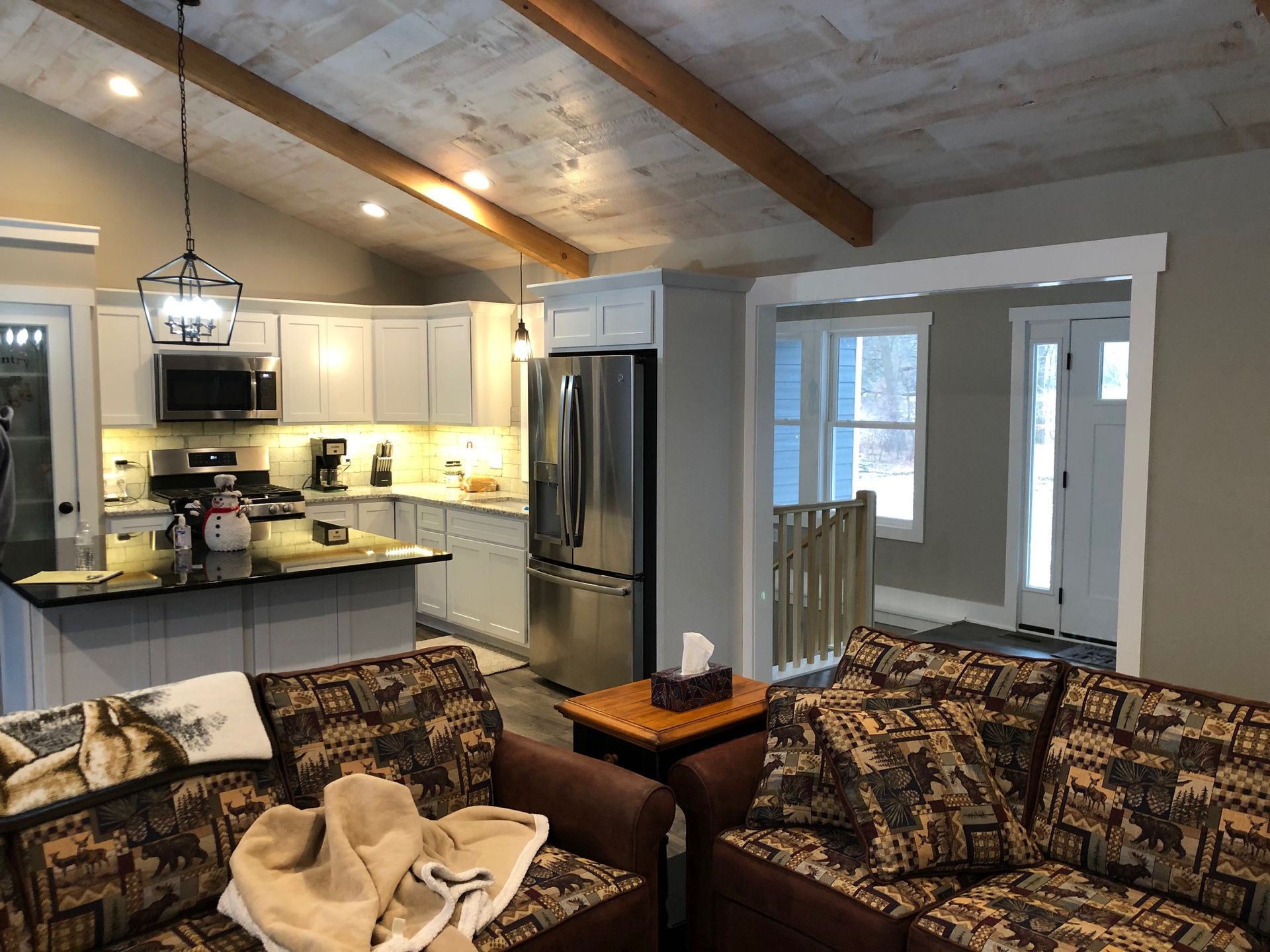 A living room filled with furniture and a kitchen with a stainless steel refrigerator.