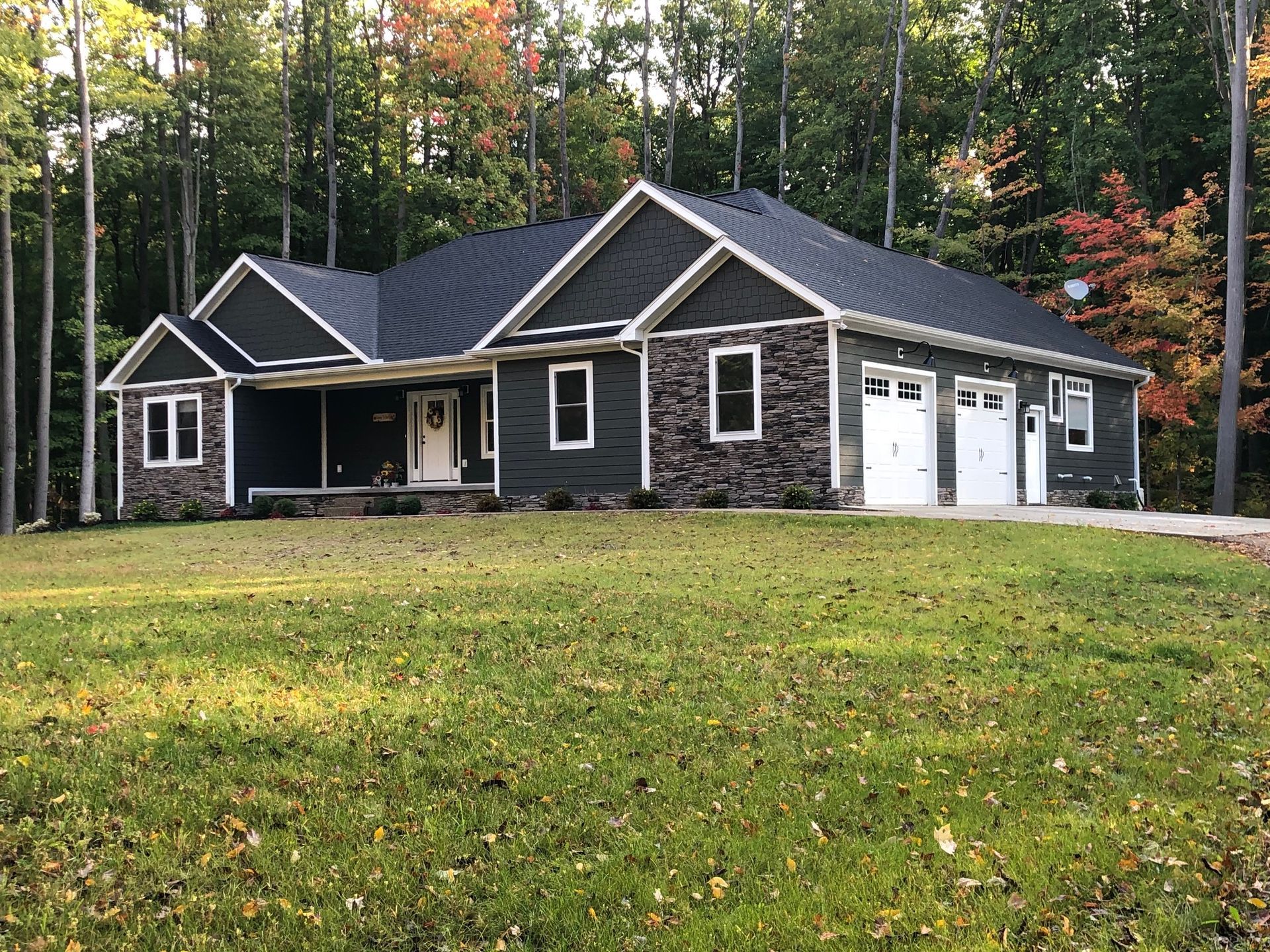 A large house is sitting on top of a lush green field surrounded by trees.