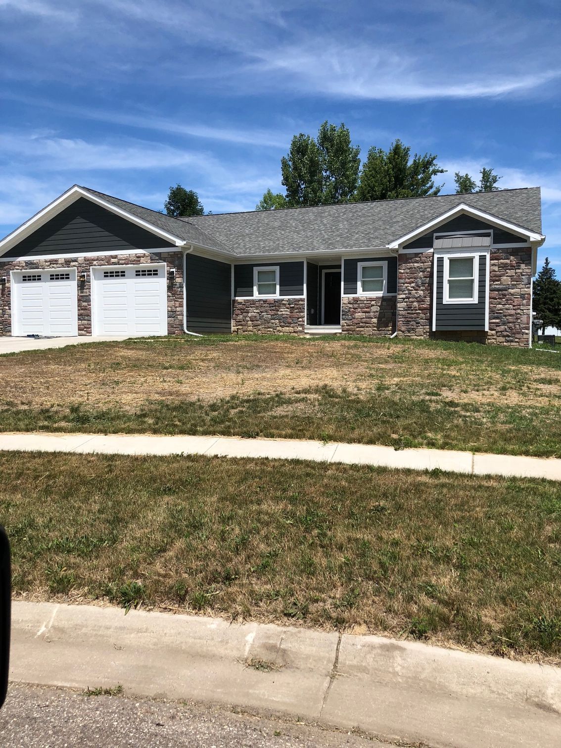 A house with a gray roof and white garage doors