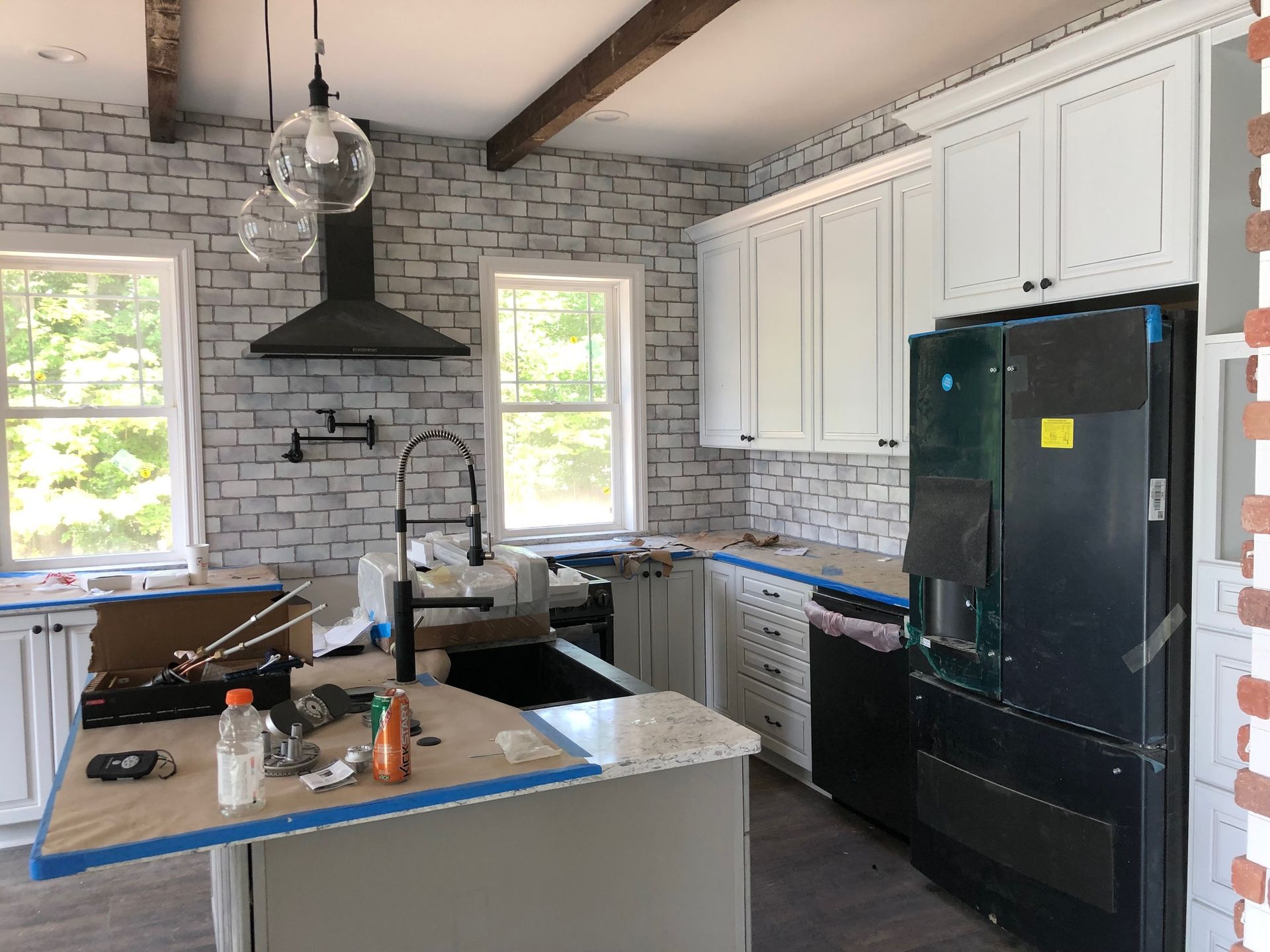 A kitchen with white cabinets and black appliances is being remodeled.