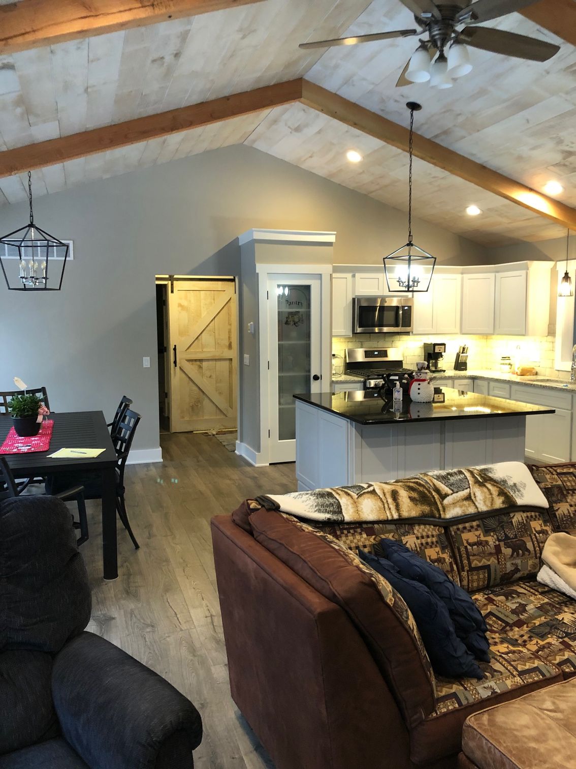A living room with a couch , chair , table and ceiling fan.